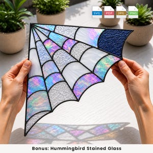 May include: A triangular stained glass panel featuring a spider web design. The piece is constructed with black metal cames and contains various glass textures, including iridescent, clear, and dark blue pebbled glass segments.