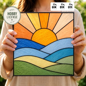 May include: A stained glass panel depicting a sunset with a yellow sun and orange rays. Below the sun are rolling hills in shades of blue, yellow, and green. The panel is framed in black and includes a "HOBBY LICENSE" sticker.