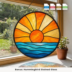 May include: A circular stained glass suncatcher featuring a vibrant orange sun rising over stylized blue ocean waves. The design includes radiating yellow and orange sunbeams set within a black metal frame, suspended by a thin metal chain.
