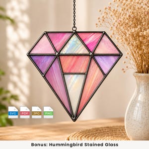 May include: A diamond-shaped stained glass suncatcher featuring various shades of pink, purple, and iridescent white glass panels held together by dark metal framing. The piece hangs from a thin black chain and includes SVG, PDF, JPG, and PNG icons.