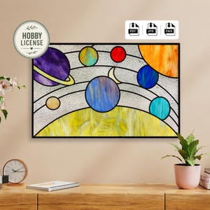 Op de afbeelding: Gebrandschilderd kunstwerk dat een kleurrijk zonnestelsel toont met planeten in paars, blauw, oranje, geel en rood. Het kunstwerk is zwart omlijst en bevat een Hobby License-logo.