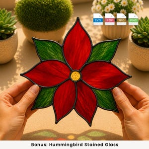 Peut inclure: Un ornement en vitrail en forme de poinsettia avec des pétales rouges vifs et des feuilles vertes texturées disposées en étoile, doté d'un centre en verre jaune. L'ensemble est bordé de soudure métallique noire pour une forme florale nette.