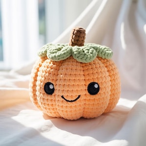 May include: A crocheted orange pumpkin with a smiling face, black eyes, and a brown stem. The pumpkin has green leaves around the top. This handmade plush is a cute fall or Halloween decoration.