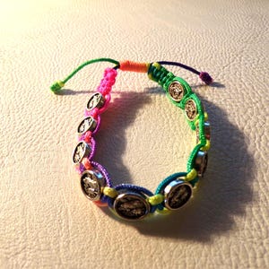 Puede incluir: Una colorida pulsera de macram&eacute; con abalorios circulares plateados. La pulsera incorpora hilos rosas, verdes, azules y amarillos, creando un accesorio vibrante y llamativo. La pulsera es ajustable con un cierre de nudo corredizo.