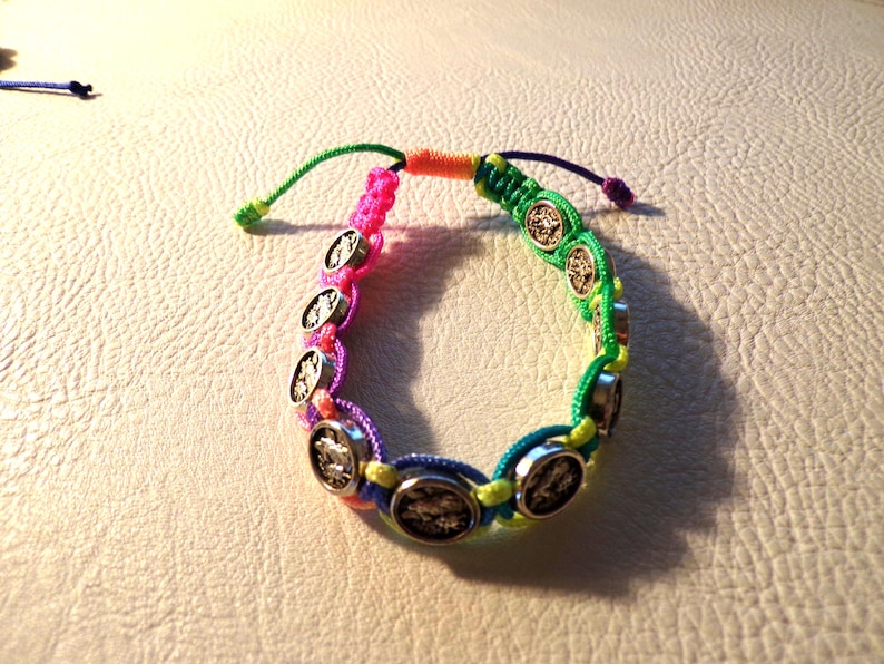Puede incluir: Una colorida pulsera de macram&eacute; con abalorios circulares plateados. La pulsera incorpora hilos rosas, verdes, azules y amarillos, creando un accesorio vibrante y llamativo. La pulsera es ajustable con un cierre de nudo corredizo.