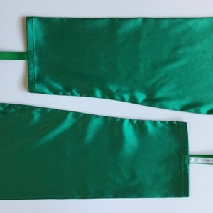 May include: Two green satin fabric arm warmers with white ribbon loops.