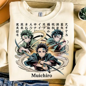 Puede incluir: Sudadera de color crema con un gráfico de tres personajes de anime con espadas y texto japonés. El personaje "Muichiro" está escrito en inglés debajo del gráfico. El diseño incluye tonos de verde, negro y beige.