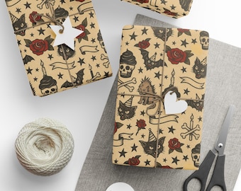 May include: Presents wrapped in paper with a tattoo-style design of skulls, roses, bats, cats, and stars. The gifts are tied with twine and have white tags. A ball of twine, scissors, and tags are also visible.