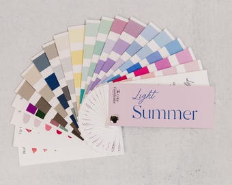 May include: A color palette fan with various shades of colors, including pinks, blues, greens, and neutrals. The fan is labeled "Light Summer" and is designed for color analysis. The palette is arranged in a semi-circle, showcasing a range of hues.
