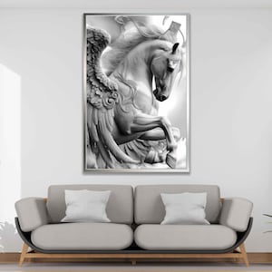 May include: Black and white framed artwork of a Pegasus, a mythical winged horse. The sculpture-like image features detailed wings and a rearing pose. The artwork is displayed above a gray sofa with white pillows, enhancing the room's decor.