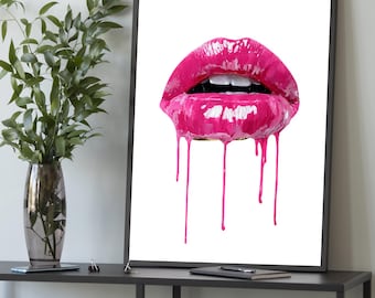 Könnte beinhalten: Gerahmter Kunstdruck mit Nahaufnahme von glänzenden, tropfenden pinkfarbenen Lippen vor weißem Hintergrund. Das Kunstwerk befindet sich in einem schwarzen Rahmen und wird auf einem dunkelgrauen Tisch präsentiert. Links ist eine Vase mit Grün.