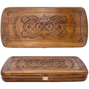 Puede incluir: Un juego de backgammon de madera con intrincados diseños tallados. El juego es de color marrón cálido, con patrones detallados en la parte superior e inferior. El juego está cerrado, mostrando el cierre de latón.
