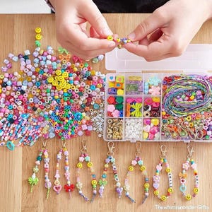 May include: A craft kit with colorful beads, smiley face beads, and keychains. The kit includes a variety of beads in different shapes and colors, including pink, yellow, green, and blue. Keychains with beaded designs are displayed.