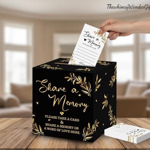 May include: Black memory box with gold floral accents and the words "Share a Memory." A hand inserts a card into the slot. The card and box feature the text "Share a Memory" and "Please take a card & share a memory or a word of love here."