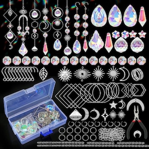 May include: A collection of jewelry-making supplies, including iridescent crystal pendants, sun and moon charms, jump rings, and a clear plastic storage box. Also included are silver-colored hooks, geometric shapes, and a pair of pliers.