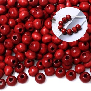 May include: A collection of round, red wooden beads with a glossy finish. The beads have a hole through the center and are scattered across the image. A close-up shows a string of beads, suggesting their use in jewelry or crafts.