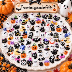 May include: A collection of small, colourful Halloween-themed resin cabochons featuring ghosts, black cats, pumpkins, skulls, haunted houses, witch hats, and candies arranged on a white plate with a sign reading ThewhimsywonderGifts.