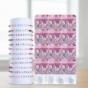 May include: A display of colorful beaded bracelets with various words and phrases, including "LUCKY," "MOLLY," and "FRIENDS." The bracelets are on a white cylinder. Also shown are small bags of beads and charms.