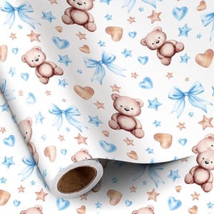 Peut inclure: Papier cadeau blanc avec un motif répété d'ours en peluche, de nœuds bleus, d'étoiles et de cœurs dans des tons de marron, de bleu et de pêche. Le papier est enroulé, révélant le motif.