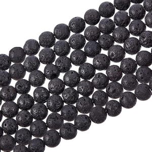 May include: Close-up of a strand of black lava rock beads. The beads are round with a porous texture and a matte finish. The beads are strung together, ready for jewelry making or other crafts.