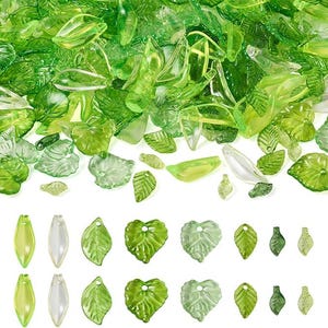 May include: A collection of translucent green leaf-shaped beads and charms. The beads vary in size and shade, from light to dark green. Some have a glossy finish, while others are more matte.