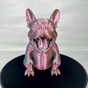 May include: A 3D-printed sculpture of a dog with its mouth wide open, showcasing its tongue and teeth. The dog has a textured, iridescent finish with shades of pink, green, and gold. It is sitting on a black circular base.