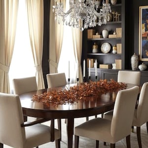 May include: Elegant dining room featuring a dark wood oval table set with six cream-colored chairs. A crystal chandelier hangs above, and the room includes a built-in bookshelf, artwork, and tall cream-colored curtains.