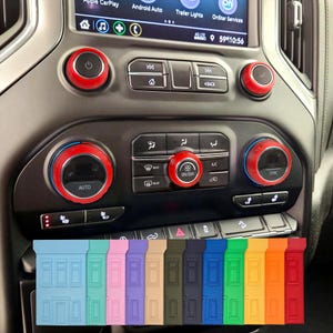 May include: Car interior with a dashboard featuring red and black accents around the controls. A variety of colored silicone door protectors are displayed at the bottom, including blue, pink, purple, and green.
