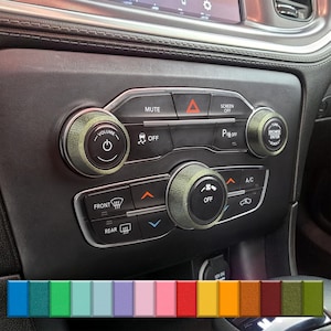 Puede incluir: Primer plano del panel de control del salpicadero de un coche con mandos de color verde oliva. El panel negro tiene botones con las etiquetas "Mute", "Screen Off", "Off" y "A/C". Los mandos controlan el volumen, la pantalla y otras funciones. Se muestra una paleta de colores en la parte inferior.