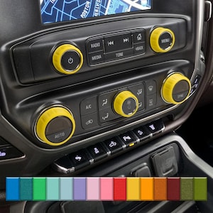 May include: A car dashboard with black panels and bright yellow control knobs. The knobs are around the radio, air conditioning, and other vehicle functions. The dashboard also has buttons and a screen displaying a map.