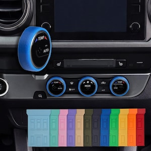Könnte beinhalten: Ein Armaturenbrett eines Autos mit blauen Zierleisten. Das Bild zeigt einen Klimaregler mit den Wörtern "TEMP" und "AUTO". Darunter befinden sich farbige Zierteile in verschiedenen Farben.