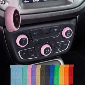 May include: Pink car interior accessories, including control knobs and a volume button. The volume button has a power symbol. A variety of colored car interior accessories are displayed below the car's dashboard.