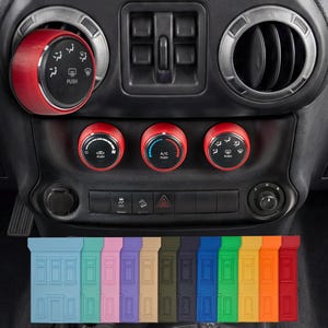 Op de afbeelding: Een autodashboard met rode bedieningsknoppen en ventilatieopeningen. De knoppen hebben witte pictogrammen en tekst. Onder het dashboard bevinden zich verschillende gekleurde rechthoekige accessoires, waaronder blauw, groen, roze, paars en oranje.