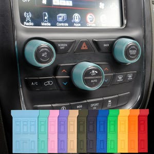 May include: A car dashboard with teal-colored control knobs and a selection of colorful, rectangular accessories. The dashboard features buttons for radio, media, and climate control. The accessories are in various colors, including blue, pink, and red.