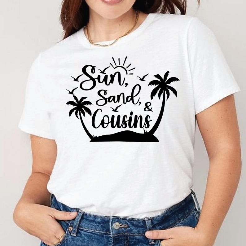 May include: White t-shirt with a black graphic design featuring the words "Sun, Sand, & Cousins" with a sun, palm trees, and birds. The shirt is made of a soft material and is suitable for casual wear.