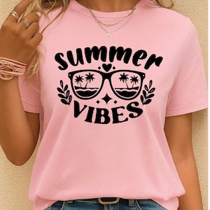 May include: A light pink t-shirt with the words "summer vibes" in black script. The design includes sunglasses with palm trees reflected in the lenses, a heart, and starbursts. The shirt is short-sleeved.