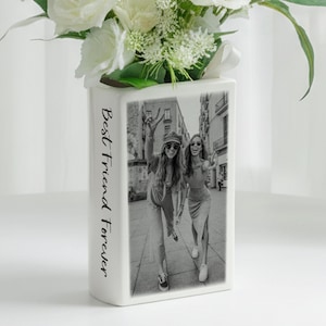 Könnte beinhalten: Rechteckige Vase aus weißer Keramik mit einem Schwarz-Weiß-Foto von zwei Frauen und dem Text "Best Friend Forever". Die Vase enthält weiße Blumen.