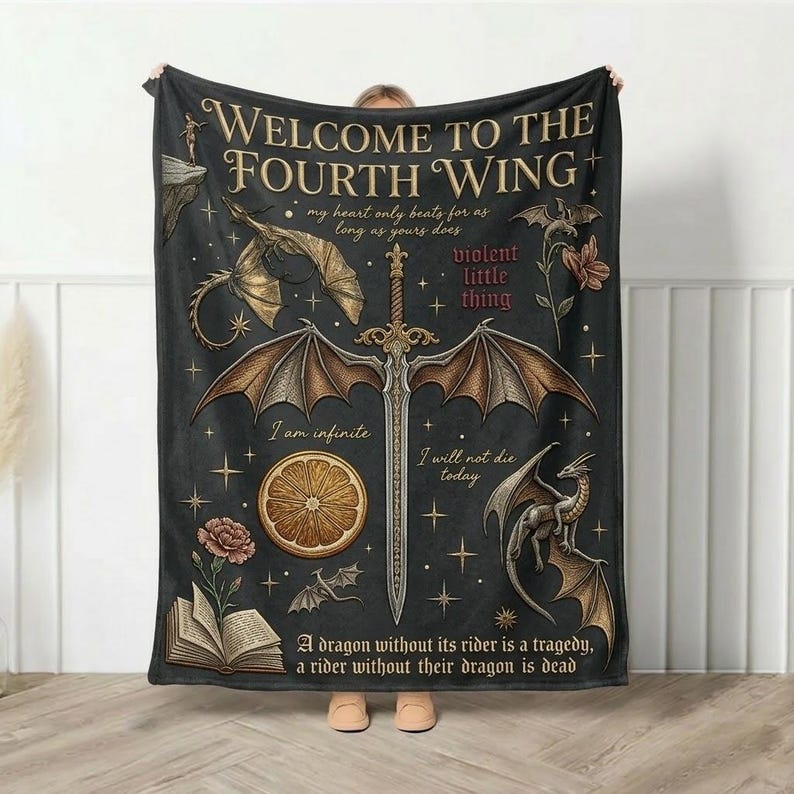 Puede incluir: Una manta negra con tem&aacute;tica de fantas&iacute;a, con una espada, dragones y el texto "WELCOME TO THE FOURTH WING". El dise&ntilde;o incluye citas e ilustraciones de flores y estrellas. La manta est&aacute; sujeta por una persona.