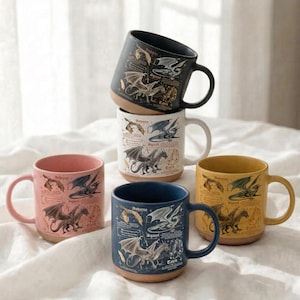 Puede incluir: Una colecci&oacute;n de tazas de cer&aacute;mica en varios colores, incluyendo rosa, azul marino, amarillo, negro y blanco. Cada taza presenta una detallada ilustraci&oacute;n de un drag&oacute;n con texto. Las tazas tienen una base marr&oacute;n contrastante y un asa curvada.