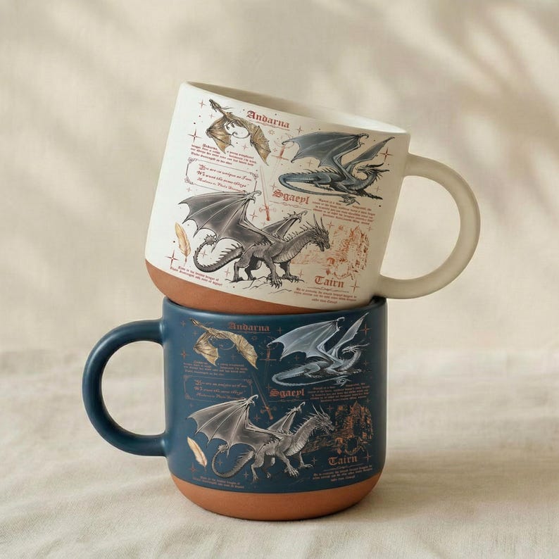 Puede incluir: Dos tazas de cer&aacute;mica apiladas. La taza superior es blanca con base marr&oacute;n y presenta ilustraciones de dragones y texto. La taza inferior es azul oscuro con base marr&oacute;n y tambi&eacute;n presenta ilustraciones de dragones y texto.