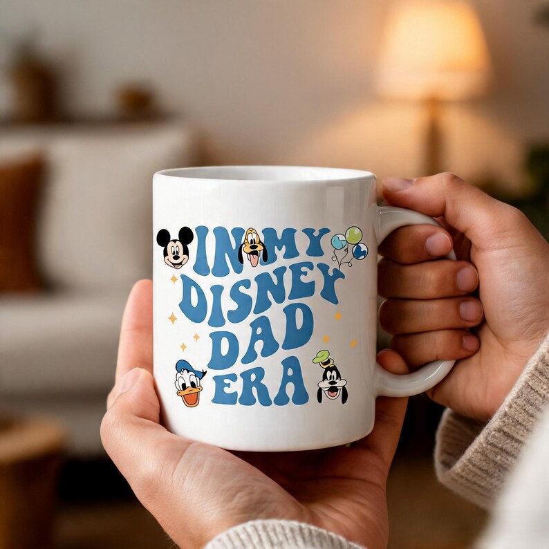Puede incluir: Una taza de cer&aacute;mica blanca con el texto azul "IN MY DISNEY DAD ERA" en una fuente ondulada. El dise&ntilde;o incluye peque&ntilde;as ilustraciones coloridas de Mickey Mouse, Pluto, Donald Duck, Goofy y tres globos, acentuadas con peque&ntilde;as estrellas amarillas.
