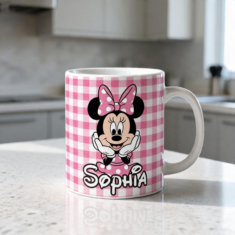 Puede incluir: Una taza de cer&aacute;mica blanca con un patr&oacute;n de cuadros vichy en rosa y blanco. El centro muestra un gr&aacute;fico de Minnie Mouse con un lazo de lunares rosa, y el nombre Sophia est&aacute; impreso en una fuente negra estilizada debajo del personaje.