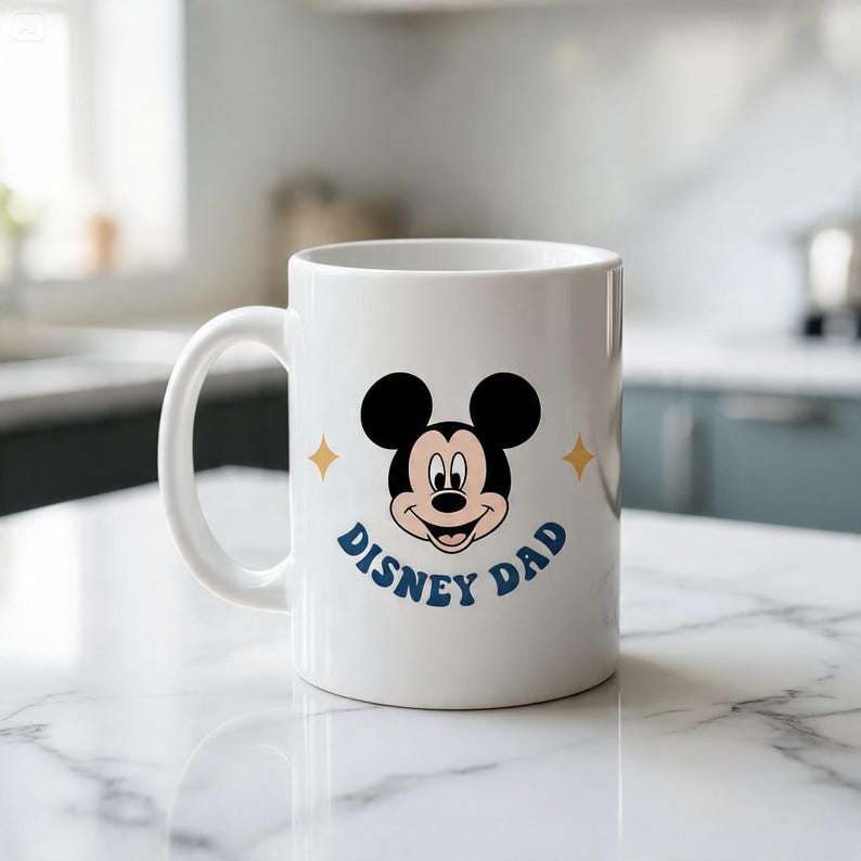 Puede incluir: Una taza de cer&aacute;mica blanca con un gr&aacute;fico de la cara de Mickey Mouse centrado sobre el texto "DISNEY DAD" en letras azules. Dos peque&ntilde;as estrellas doradas de cuatro puntas est&aacute;n situadas a ambos lados de la cabeza del personaje.
