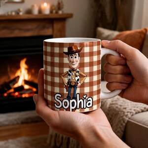 May include: A white ceramic mug featuring a brown and cream checkered pattern. The mug displays a graphic of a cowboy character wearing a hat, vest, and badge, with the name Sophia printed in white letters below the character.