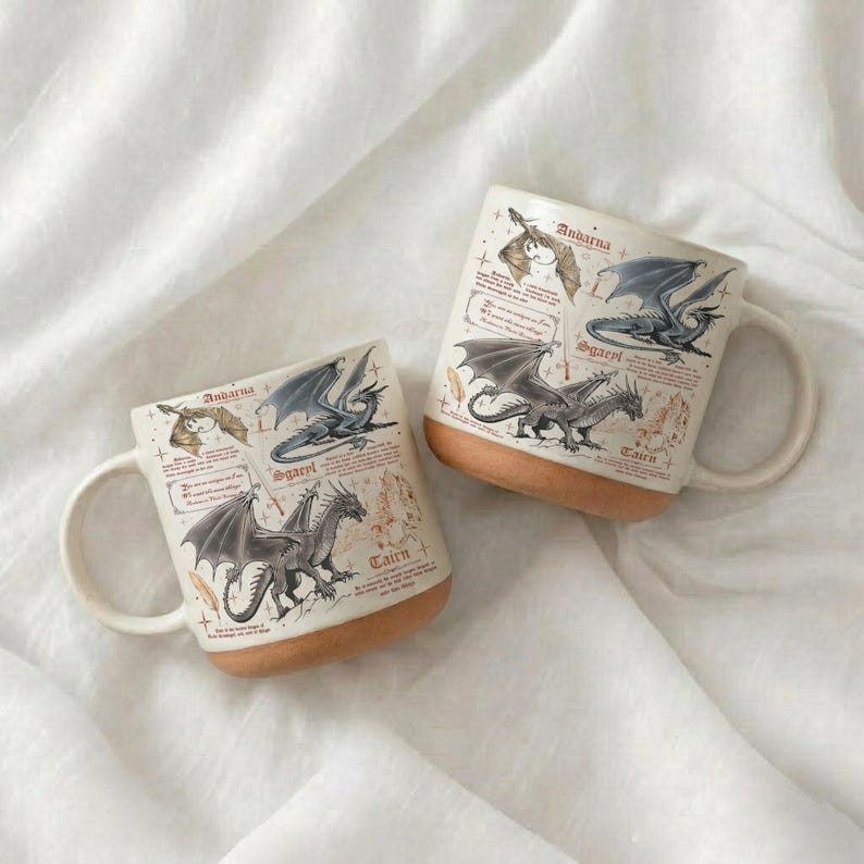 Puede incluir: Dos tazas de cer&aacute;mica blanca con base beige, con ilustraciones de dragones y texto. Las ilustraciones de dragones son en tonos grises y negros. Las tazas est&aacute;n sobre una superficie blanca texturizada.
