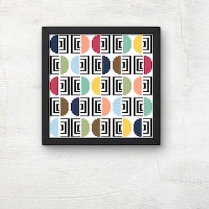 May include: A framed print with a geometric pattern. The design features a repeating arrangement of colorful half-circles in shades of red, orange, yellow, green, blue, and brown, set against a black and white background. The frame is black.