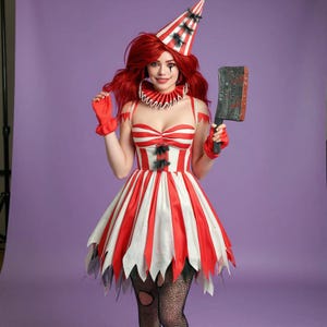 May include: A red and white striped clown costume with a matching hat and gloves. The dress has a sweetheart neckline and a jagged hemline. The costume includes a prop cleaver. The model is wearing a red wig and fishnet stockings.