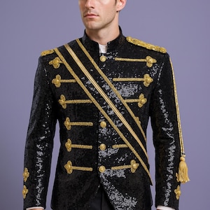 May include: Black sequined jacket with gold trim, epaulets, and decorative buttons. The jacket features a mandarin collar and a gold sash. A tassel hangs from the right shoulder. The formal wear jacket is suitable for a costume or special event.