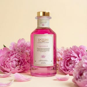 May include: A pink glass bottle with a gold cap, filled with a pink liquid, and a white label with the text "FXTEINI" and "FLAFONISH BLISS". The bottle is surrounded by pink peony flowers and petals.