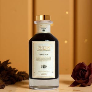 Peut inclure: Une bouteille en verre foncé avec un bouchon doré et une étiquette blanche portant le texte "FXTEINI GROUP ILLUMINATE YOUR SENSES" et "PERISSA NOIR". La bouteille est remplie d'un liquide foncé et repose sur une surface réfléchissante.